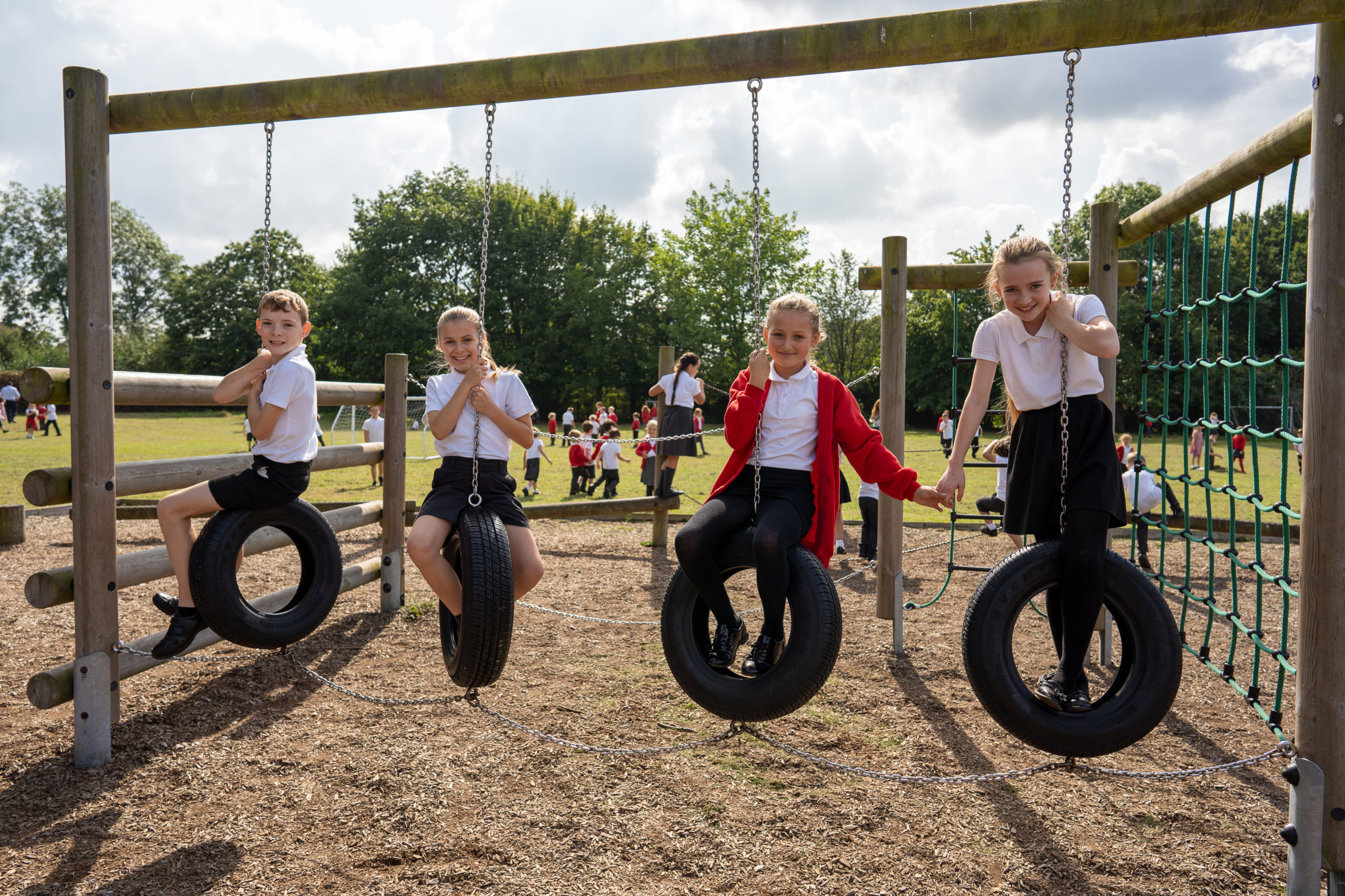 Four pupils, three girls and a boy can be seen hanging onto tyres on chains in the school playground and smiling for the camera.