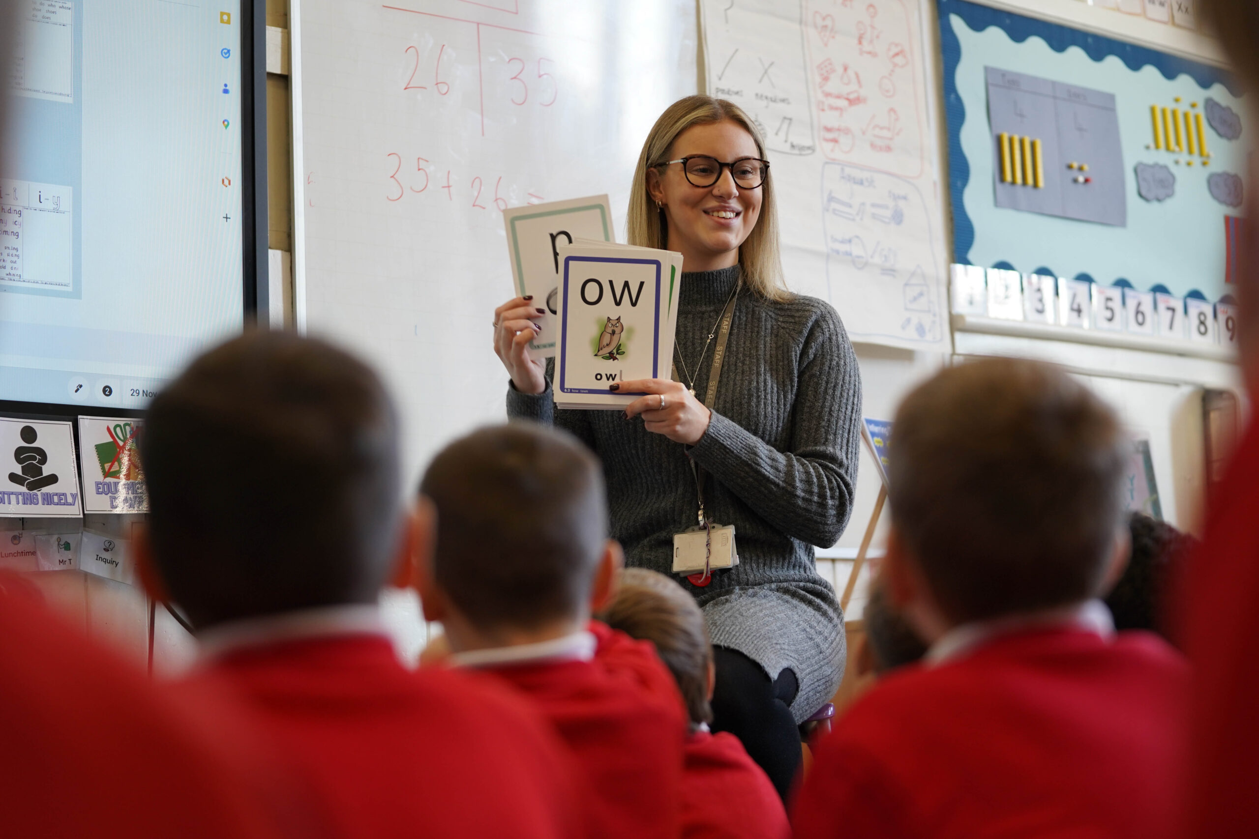 Children sat on the floor looking at a teacher