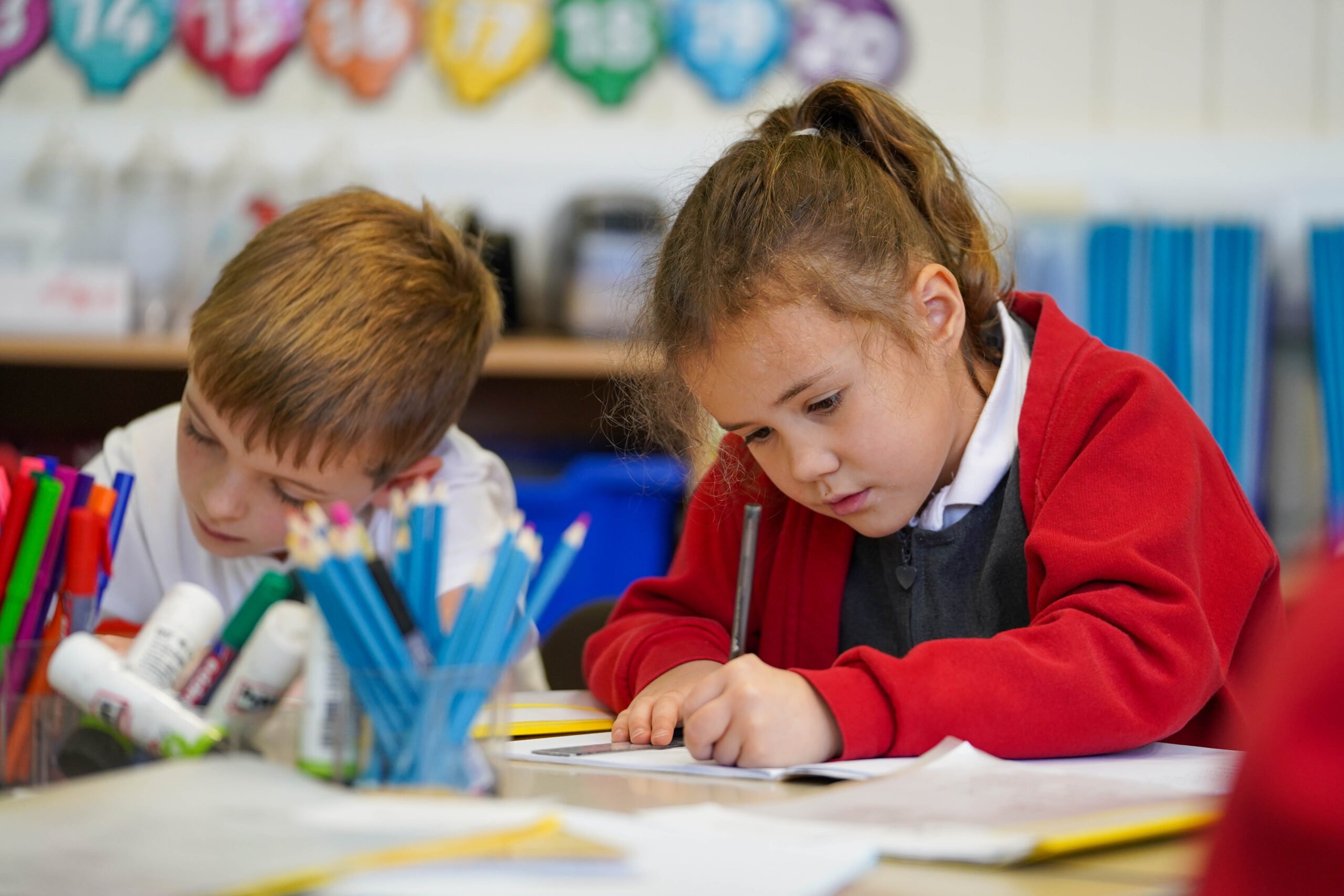 Two students at a desk writing